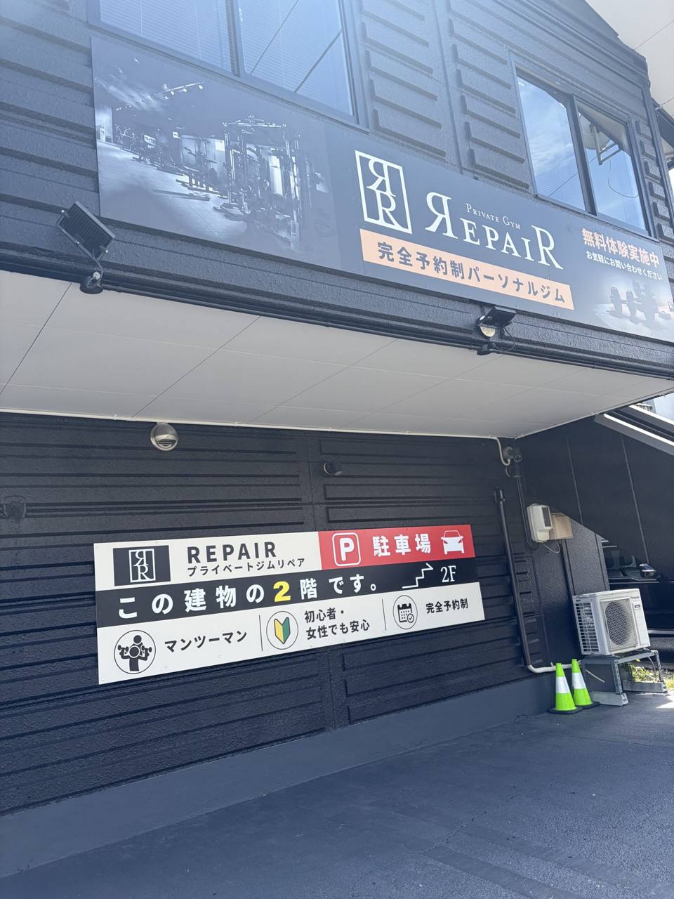 中川ビルの外観。「この建物の2階です」と駐車場の看板